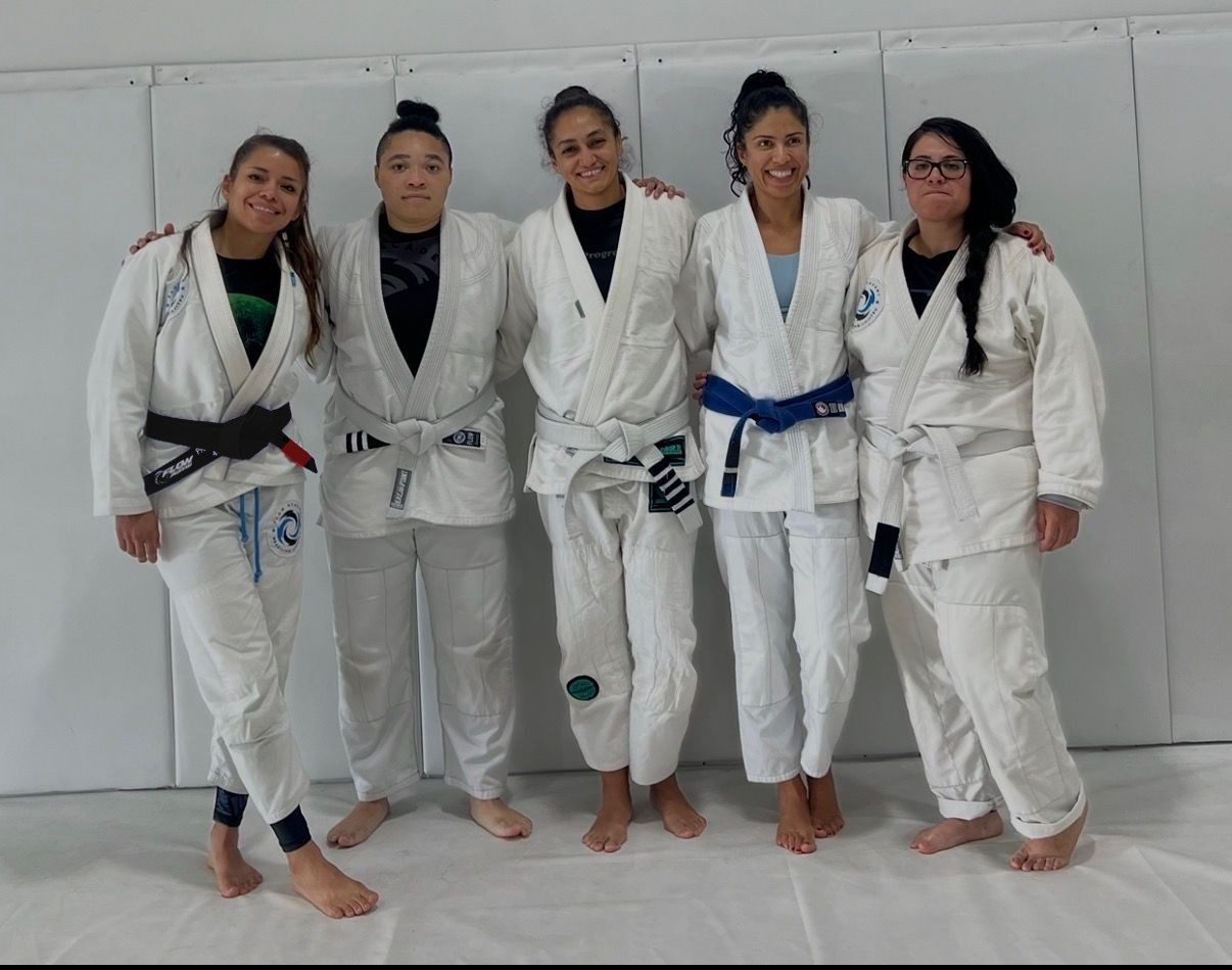 Zaide with four women in white gis, standing arm in arm on the mat